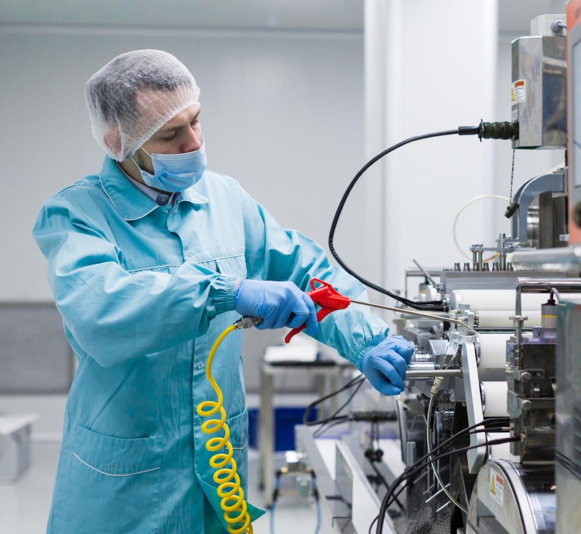 man in blue uniform, mask, and hair net operating a machine